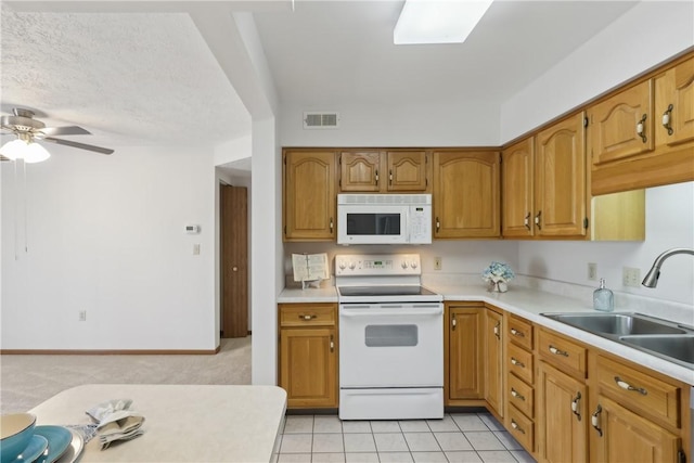 kitchen featuring light countertops, white appliances, visible vents, and a sink