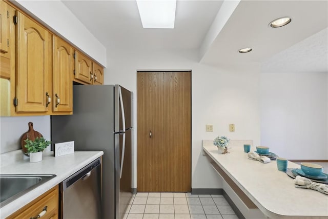 kitchen featuring a peninsula, light tile patterned floors, light countertops, and dishwasher