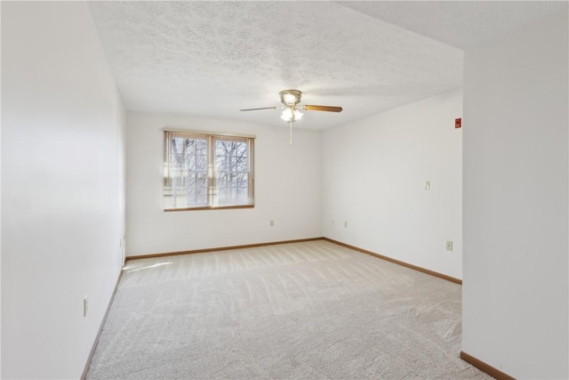 empty room featuring carpet floors, ceiling fan, a textured ceiling, and baseboards