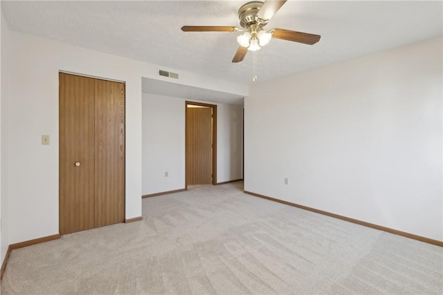 unfurnished bedroom with a closet, visible vents, a ceiling fan, light carpet, and baseboards