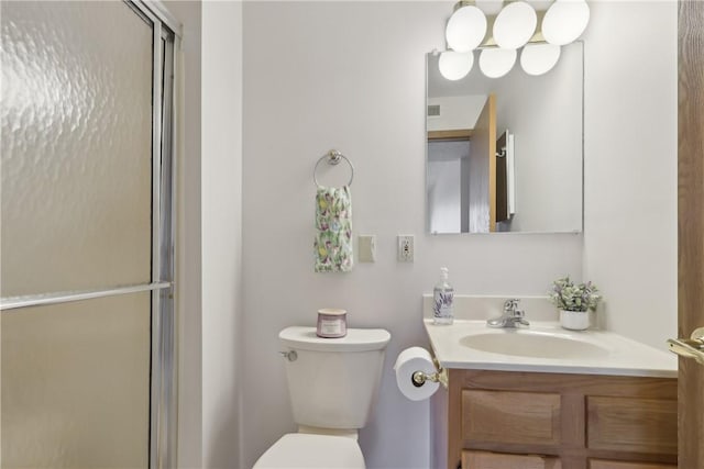 bathroom with a shower with shower door, vanity, and toilet