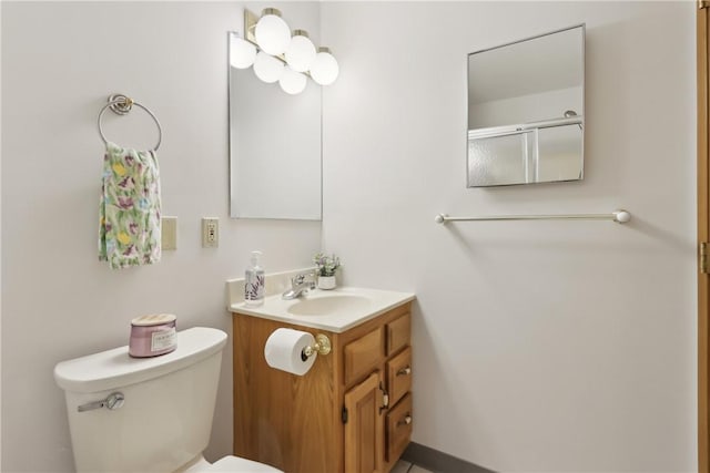 bathroom with toilet, a shower with shower door, and vanity