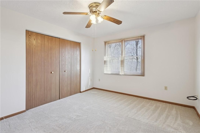 unfurnished bedroom with carpet floors, a closet, a ceiling fan, and baseboards