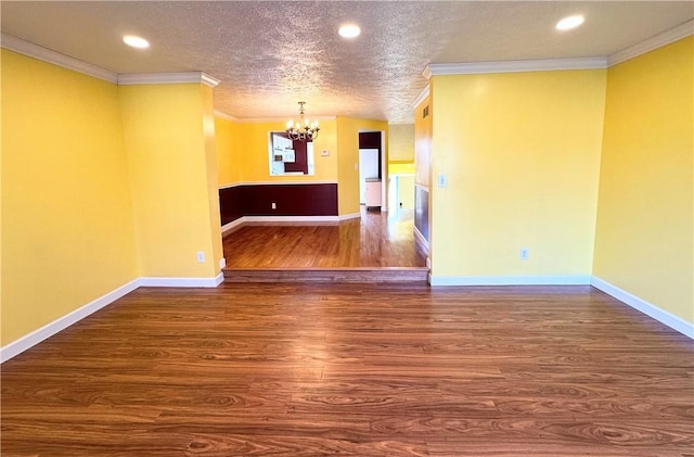 unfurnished room featuring a chandelier, baseboards, wood finished floors, and crown molding