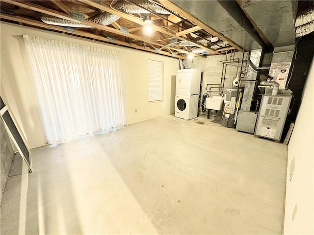 unfinished basement with gas water heater, a sink, and stacked washer / drying machine