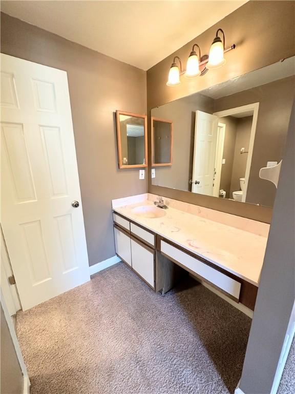 bathroom with baseboards, vanity, and toilet