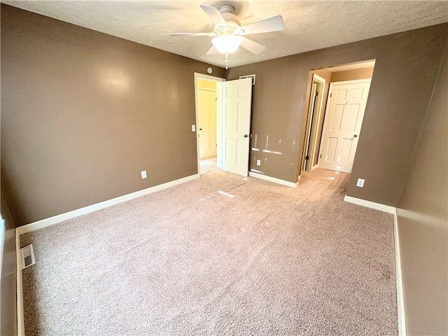 unfurnished bedroom featuring a textured ceiling, ceiling fan, light colored carpet, and baseboards