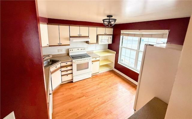 kitchen featuring tasteful backsplash, light wood-style flooring, a sink, white appliances, and under cabinet range hood