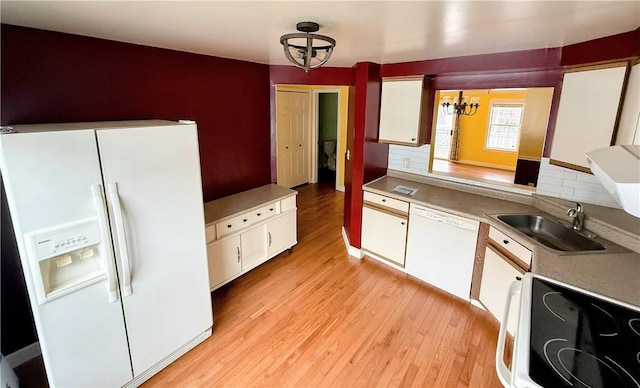 kitchen with white appliances, a sink, white cabinetry, and light wood-style floors