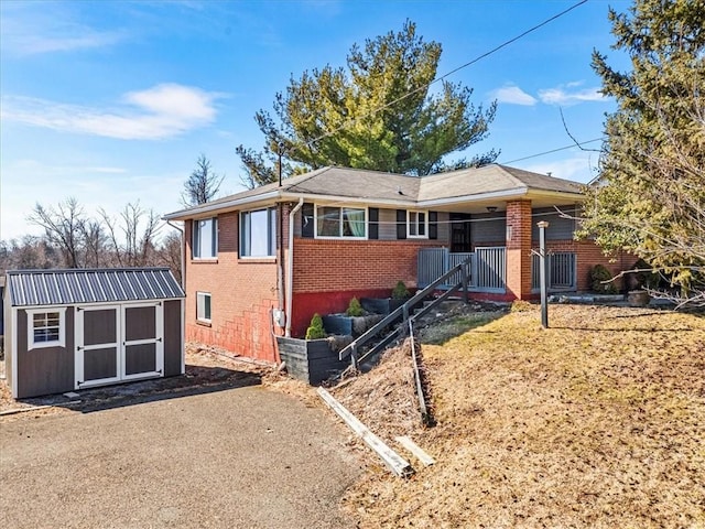 ranch-style home featuring a storage shed, brick siding, and an outbuilding