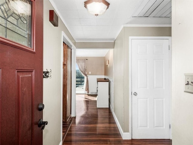 corridor with baseboards, ornamental molding, and dark wood finished floors