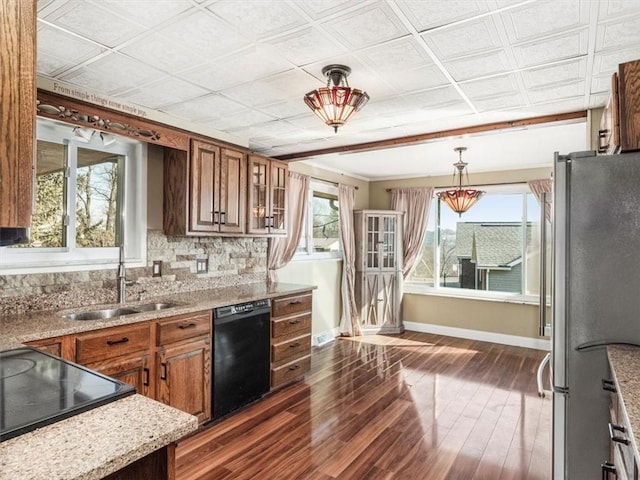 kitchen featuring brown cabinetry, freestanding refrigerator, dishwasher, and a sink