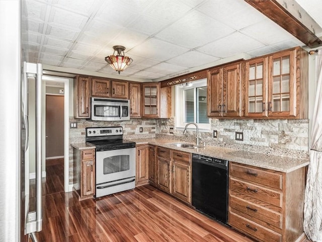 kitchen with dark wood-style flooring, a sink, appliances with stainless steel finishes, light stone countertops, and brown cabinetry