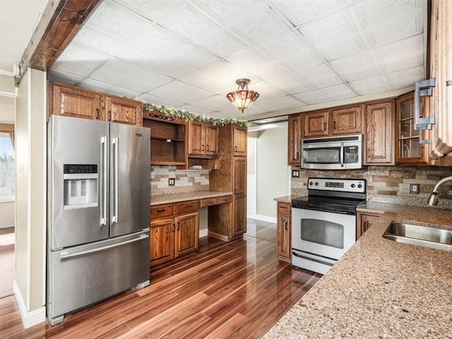 kitchen featuring brown cabinets, dark wood finished floors, open shelves, stainless steel appliances, and a sink