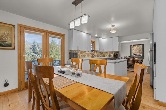 dining area featuring french doors, baseboards, and light wood finished floors