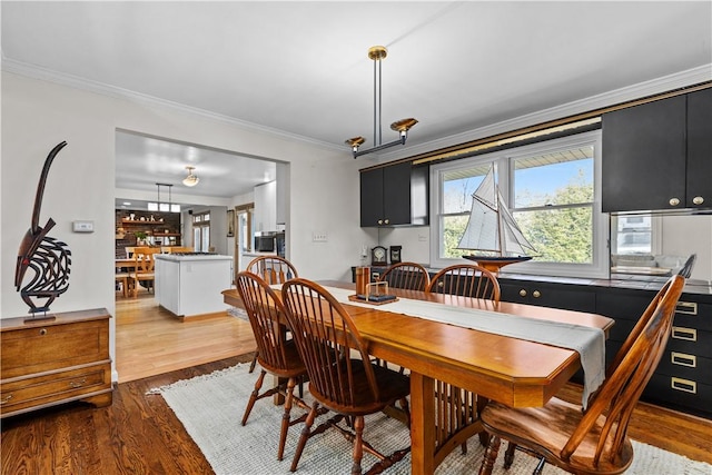 dining area featuring light wood-type flooring and ornamental molding