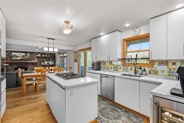 kitchen featuring a sink, a center island, stainless steel appliances, white cabinets, and light countertops