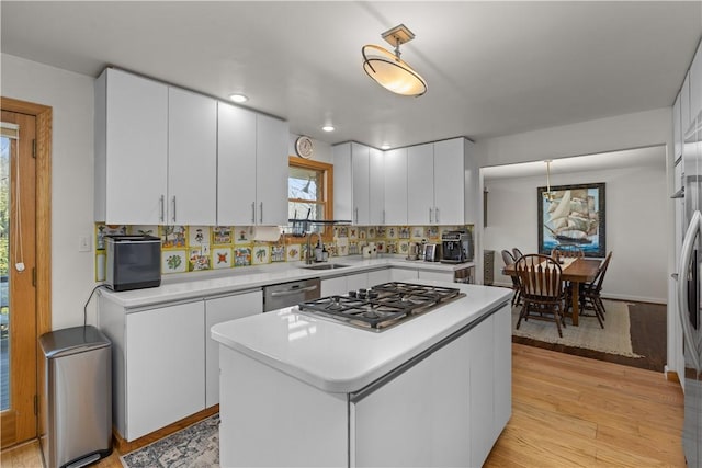 kitchen featuring stainless steel appliances, a sink, light countertops, white cabinets, and light wood-type flooring