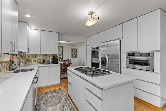 kitchen featuring white cabinetry, light wood-style floors, appliances with stainless steel finishes, and a sink