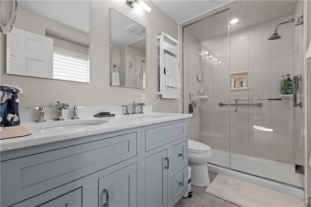 full bathroom with double vanity, a stall shower, toilet, and a sink