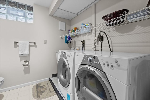 washroom with tile patterned flooring, baseboards, laundry area, and washing machine and clothes dryer