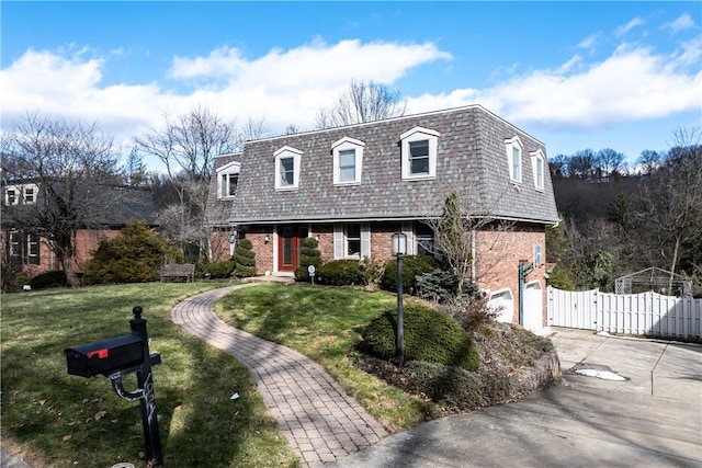 view of front of property featuring brick siding, an attached garage, mansard roof, driveway, and a gate