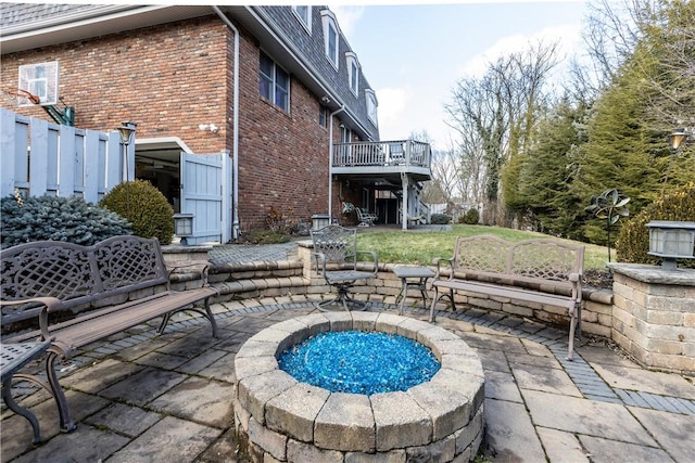 view of swimming pool featuring a wooden deck, an outdoor fire pit, a patio, and fence