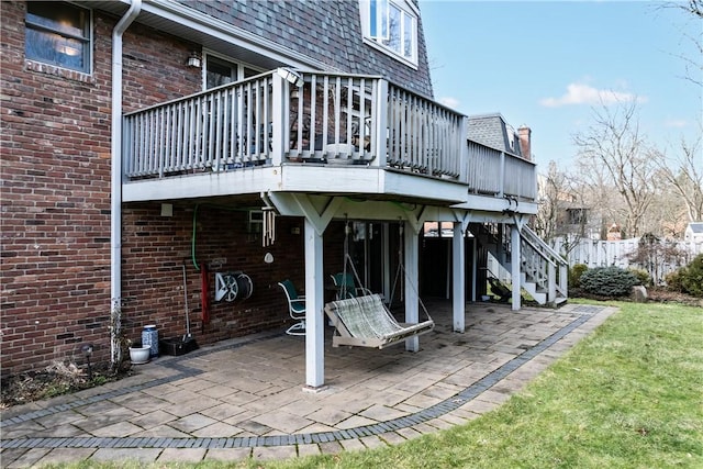 rear view of property with stairway, a patio area, roof with shingles, and a wooden deck