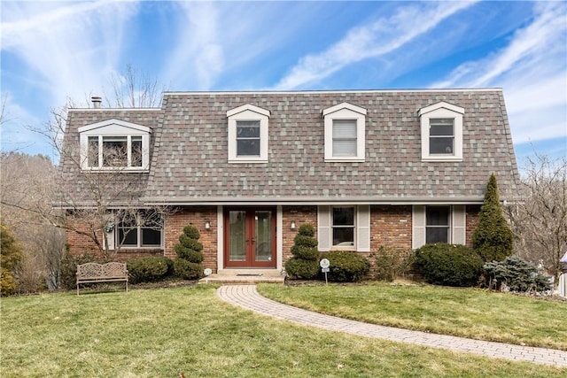 view of front of house with brick siding, french doors, a shingled roof, and a front lawn