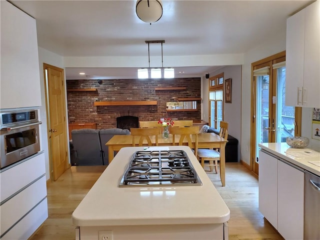 1921 Garrick Dr, Churchill Boro, PA 15235 - kitchen featuring appliances with stainless steel finishes, light wood-type flooring, white cabinetry, light countertops, and brick wall