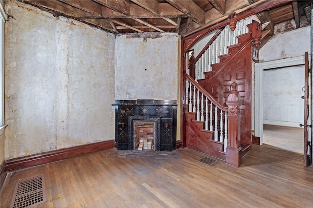 below grade area featuring visible vents, baseboards, hardwood / wood-style floors, and stairway