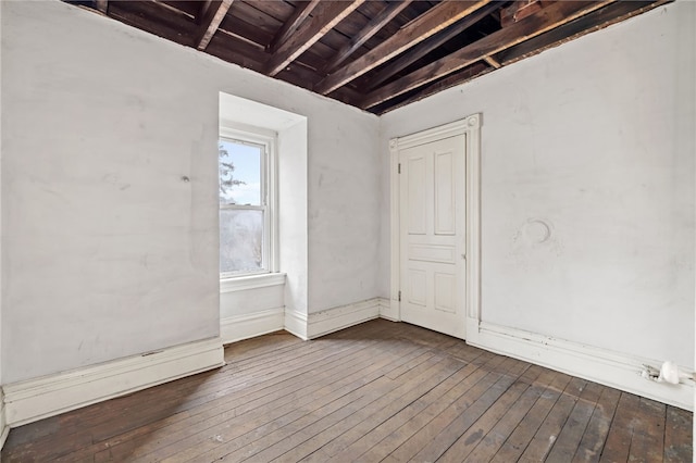 empty room featuring beamed ceiling and hardwood / wood-style flooring