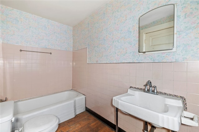 full bathroom with toilet, a sink, wood finished floors, wainscoting, and wallpapered walls