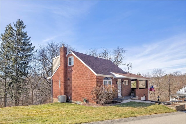 view of front facade featuring brick siding, a chimney, a front yard, and central air condition unit