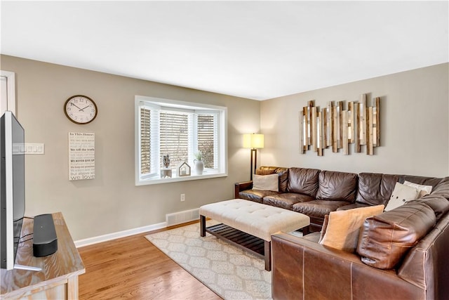 living area featuring light wood-type flooring, visible vents, and baseboards