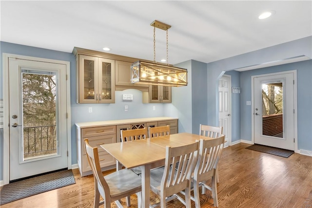 dining space with arched walkways, recessed lighting, baseboards, and light wood-style floors