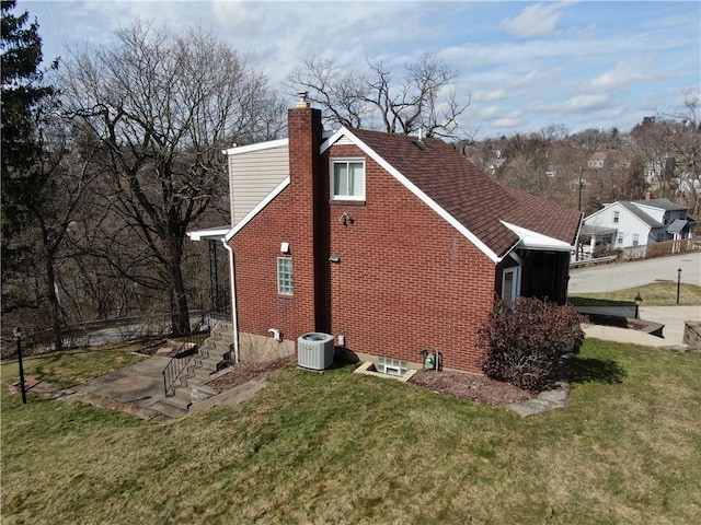 view of home's exterior with a chimney, stairs, a yard, central air condition unit, and brick siding