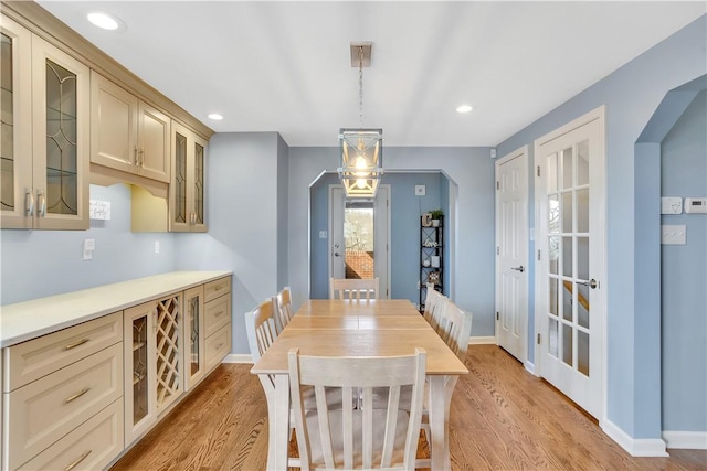 dining space featuring light wood-style floors, baseboards, arched walkways, and recessed lighting