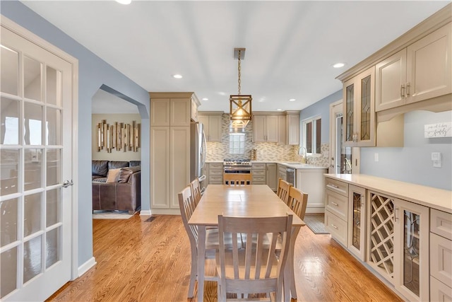 dining area with light wood-type flooring, arched walkways, and recessed lighting