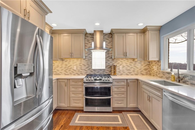 kitchen with wall chimney range hood, stainless steel appliances, a sink, and light countertops