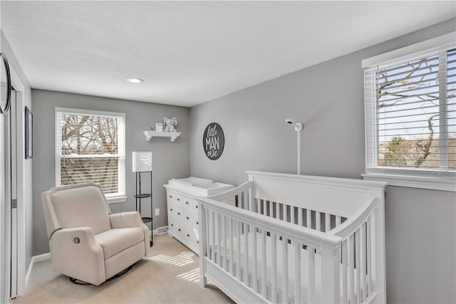 bedroom with carpet, a crib, and baseboards