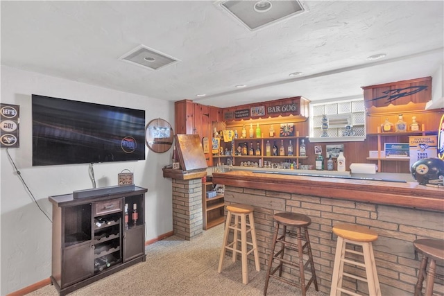 bar featuring baseboards, carpet flooring, visible vents, and a bar