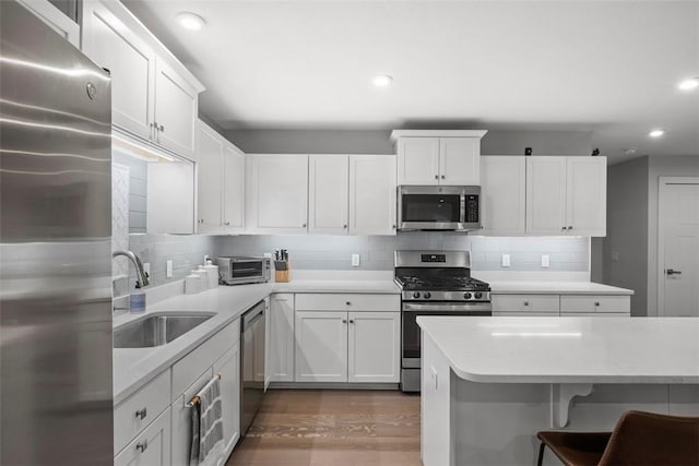 kitchen with appliances with stainless steel finishes, backsplash, a sink, and white cabinetry