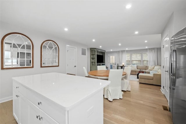 kitchen with recessed lighting, light wood-type flooring, stainless steel fridge, and white cabinets