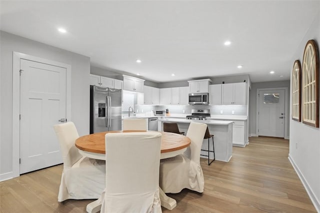 dining room featuring light wood-style flooring, baseboards, and recessed lighting