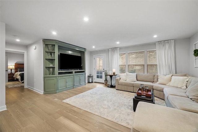 living room featuring baseboards, light wood finished floors, and recessed lighting