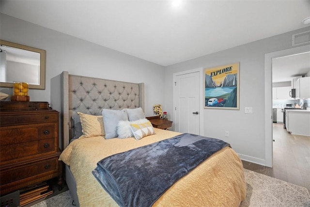 bedroom with baseboards, visible vents, and wood finished floors