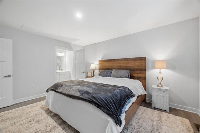 bedroom featuring ensuite bath, wood finished floors, and baseboards