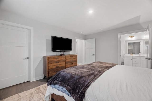 bedroom with baseboards, wood finished floors, and connected bathroom