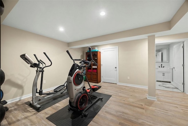 exercise area featuring light wood finished floors, baseboards, and recessed lighting